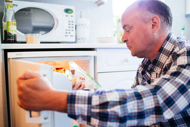 Man taking a sandwich out of a fridge to check the food label