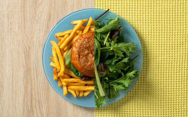 Plate with burger and chips on one half and salad on the other