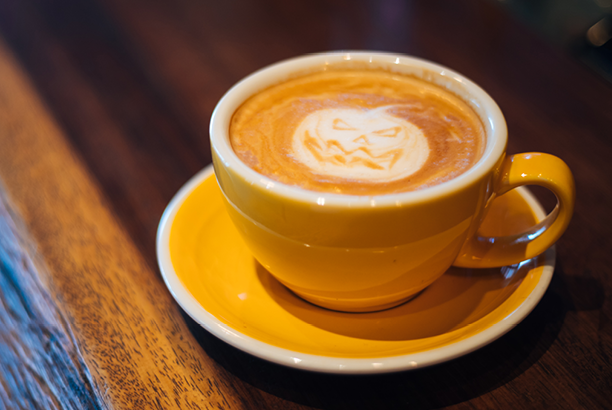 Cup of coffee with a Jack O' Lantern design in the foam