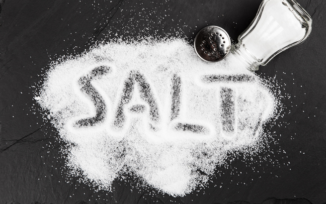 Spilled salt cellar with the word salt written in the grains 