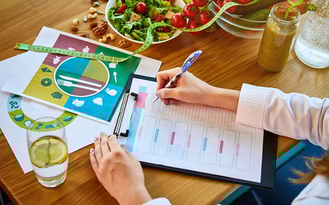 A table with a clipboard and some healthy food