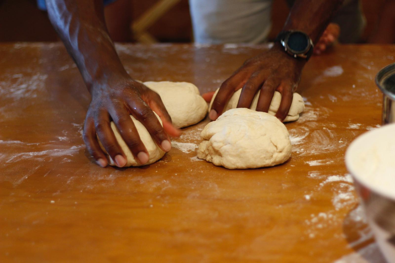 A man handling four balls of pizza dough