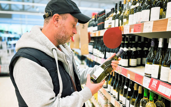 Mid adult man looking at wine in supermarket