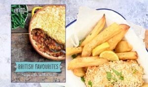 A cookery book cover titled British Favourites next to a plate of breaded fish with thick-cut chips, garnished with lemon wedges and herbs. The cookery book features a baked pie with a golden crust and a savoury filling.