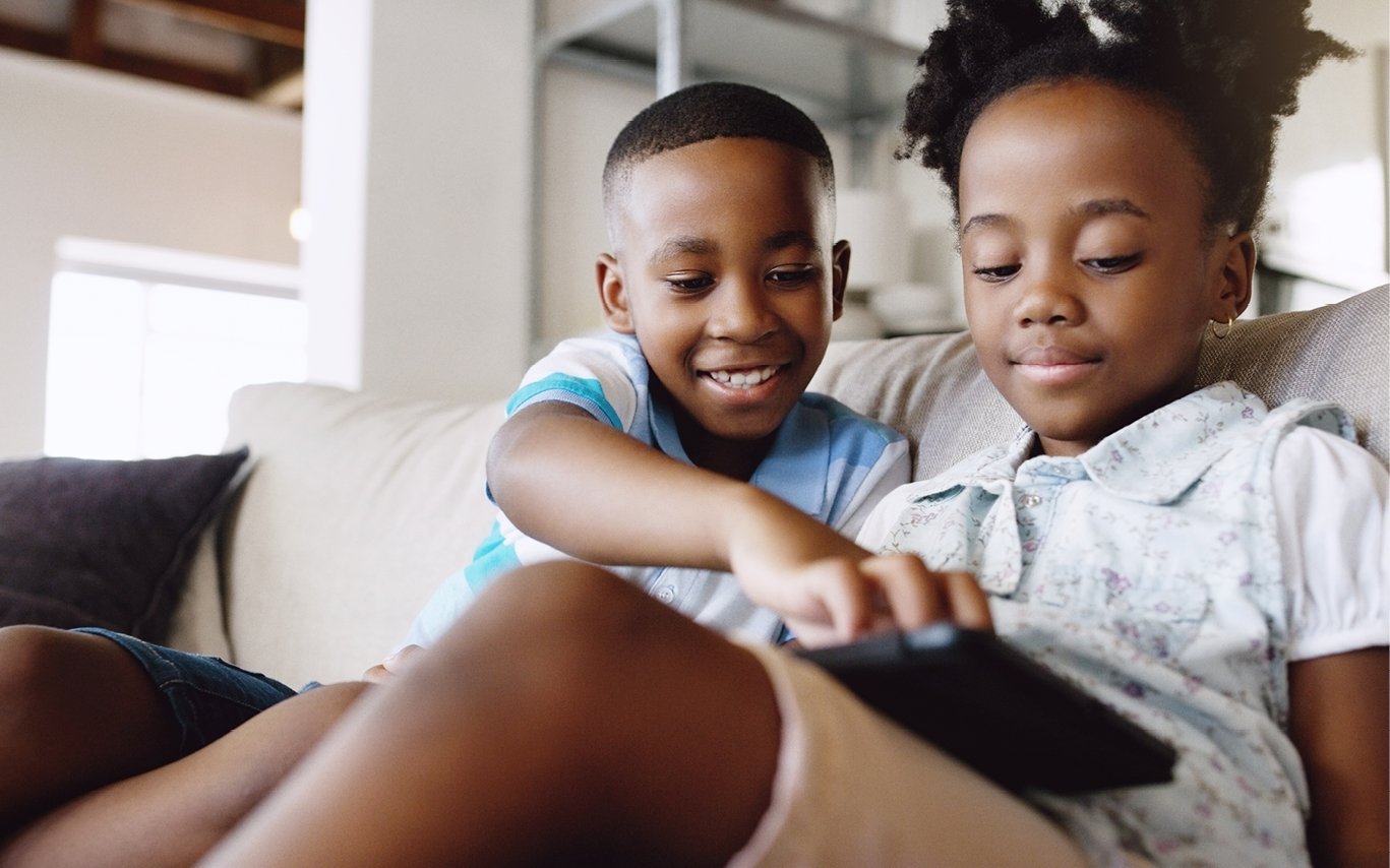 A young boy and girl wrestling over a remote control
