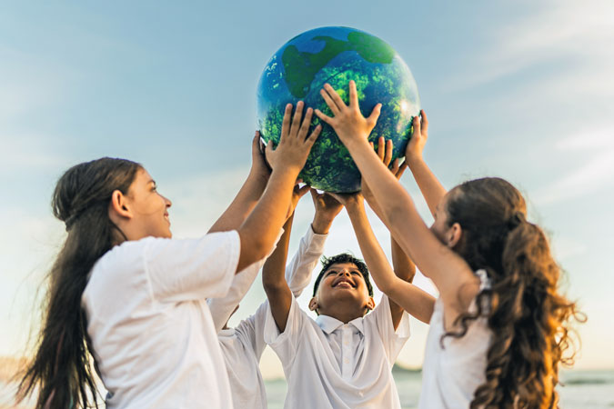 Children holding a planet on the beach