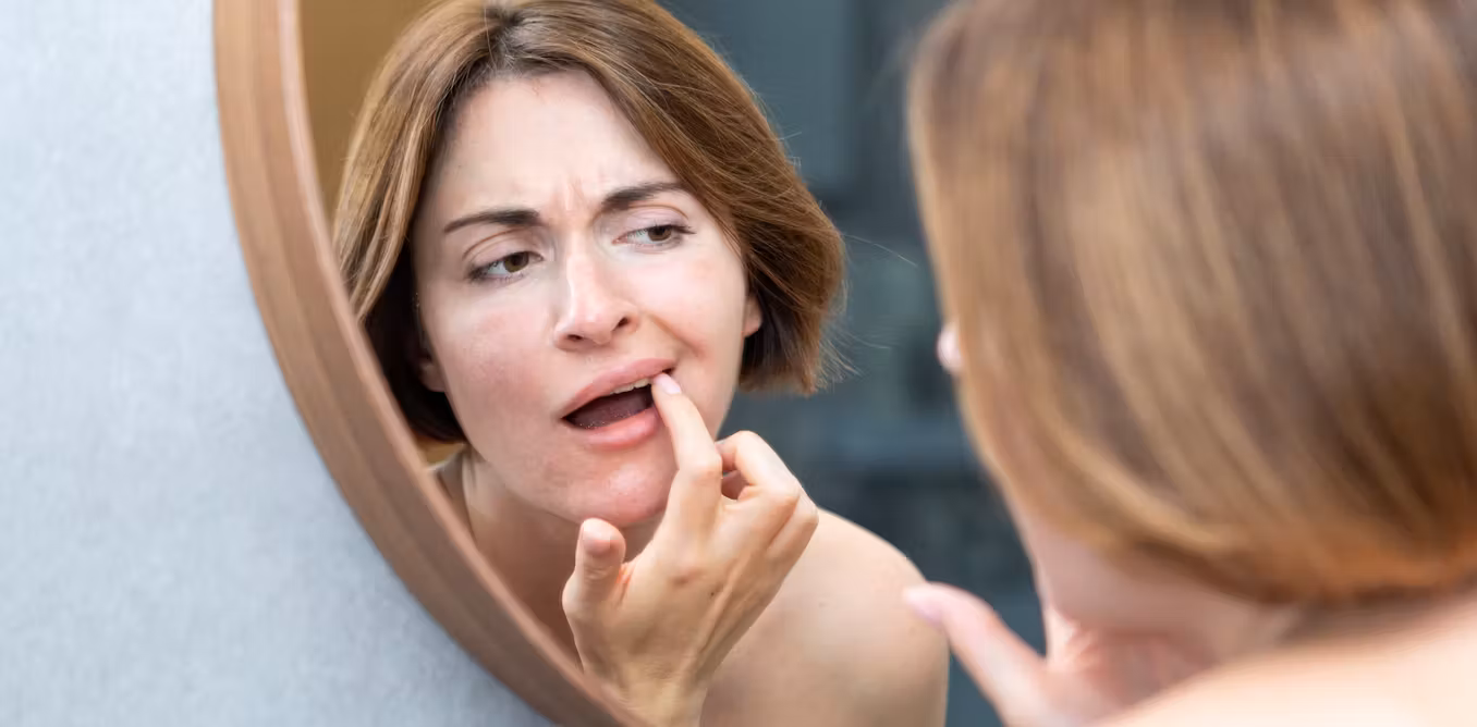 A woman checks her mouth for signs of cancer