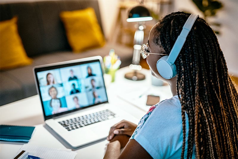 A girl with headphones on a laptop in an online meeting