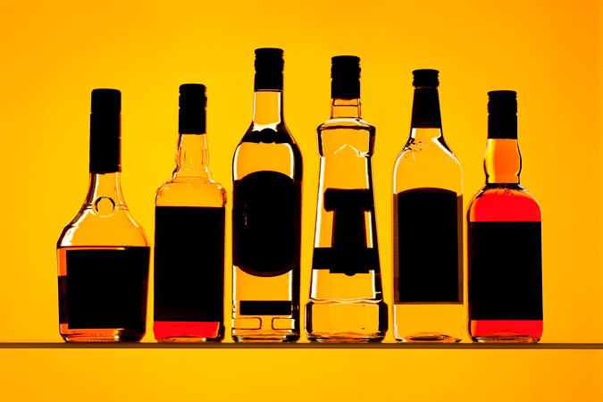 Silhouettes of drinks bottles against a yellow background