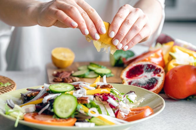A woman makes a fresh vegetable salad, close-up.