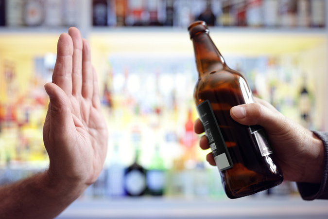someone putting their hand up saying no when offered a bottle of beer