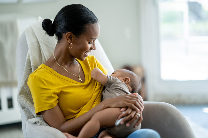 A woman in a yellow top breastfeeding her baby
