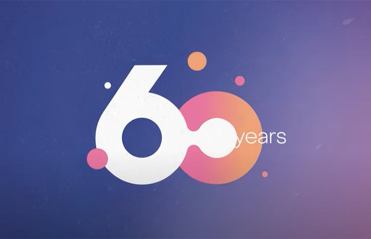 White 60 years anniversary logo on a purple gradient background, with orange and pink circles incorporated into the design for a modern, celebratory look.