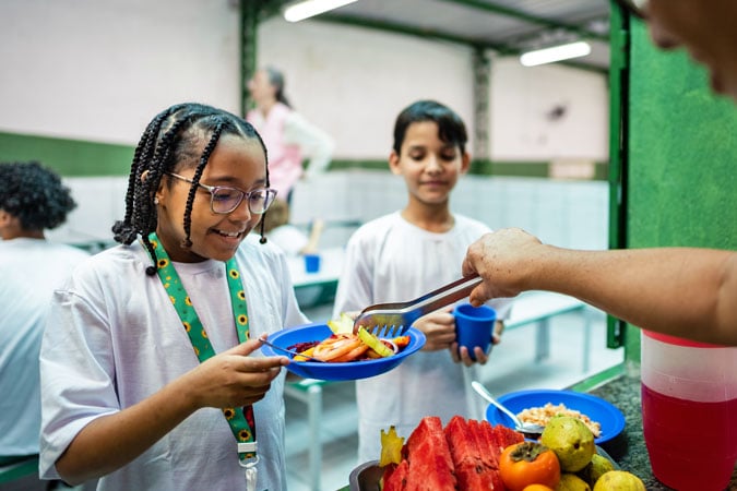 Schoolgirl being served with healthy lunch in the cafeteria at school - Including people with autism