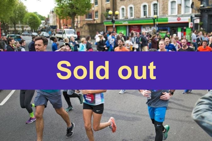 Runners participating in a crowded street race with spectators watching; a large purple banner with the words “Sold out” covers the centre of the image.