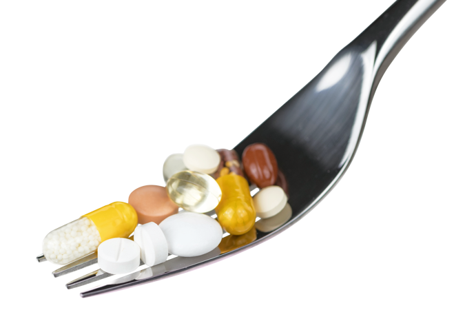 A close-up of a metal fork holding various pills and capsules of different shapes, sizes, and colours, set against a plain white background—symbolising cancer prevention resources for health professionals.