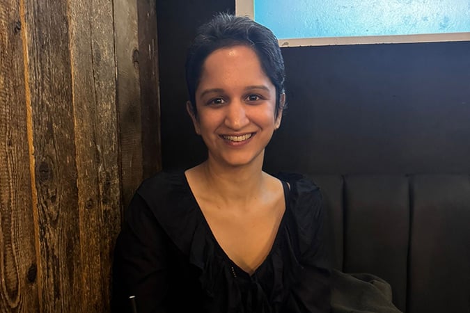 A smiling woman sits in a restaurant booth, seemingly relieved following a breast cancer scare.