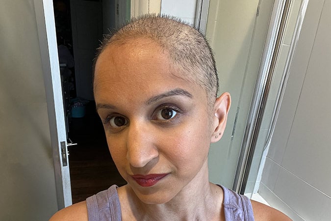 A person with a shaven head following a breast cancer scare looking at the camera.