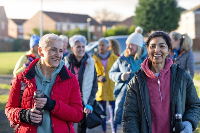 A group of young people walking together outdoors in sportswear to support cancer awareness.